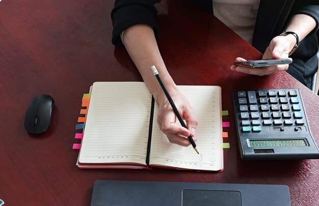 A person working on planning with a pen in hand and calculator visible.