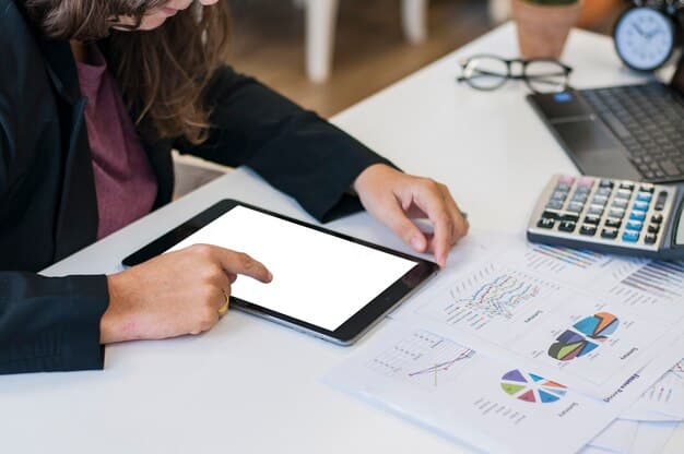 A close-up shot of a person's hands using a calculator and reviewing a budget spreadsheet on a tablet. The background is blurred, focusing on the financial planning aspects.