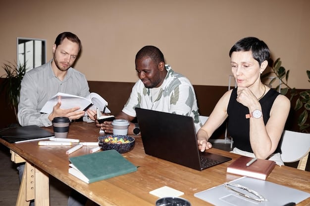 A diverse group of people collaborating around a table, some looking at laptops and others engaged in discussion, symbolizing teamwork and skill-sharing in a professional environment.