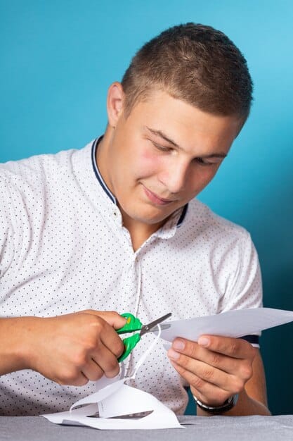 A person filling out a loan forgiveness application form with a pen, set against a backdrop of organized documents and a focused expression.