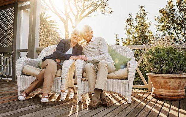 A serene image of an elderly couple sitting on a porch, smiling, with a lush green garden in the background. They are holding hands, symbolizing financial security and a comfortable retirement, emphasizing the importance of retirement accounts.