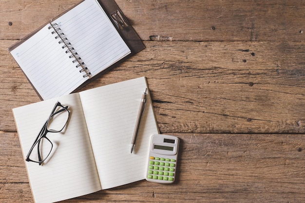 A calculator, a pen, and a notebook showing budget calculations laid out on a wooden table with a cup of coffee. The lighting should be natural, highlighting the details of the financial planning tools.