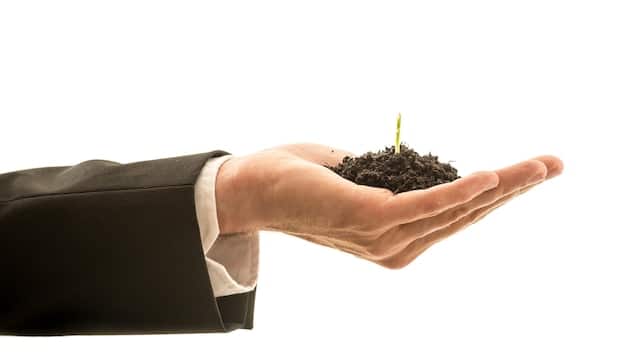 A close-up of a hand holding a seedling in fertile soil, symbolizing the growth and potential of long-term investments for retirement.