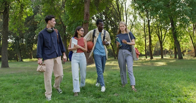 A diverse group of college students walking across a campus lawn with backpacks and books, symbolizing the future beneficiaries of 529 plans.